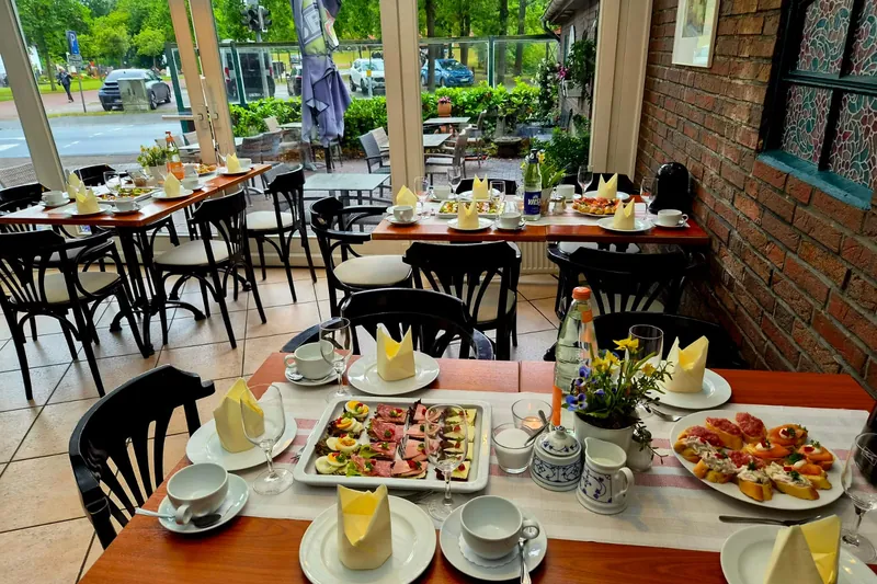Gedeckte Tische mit belegten Broten und Kaffeegedeck, dahinter die Terrasse