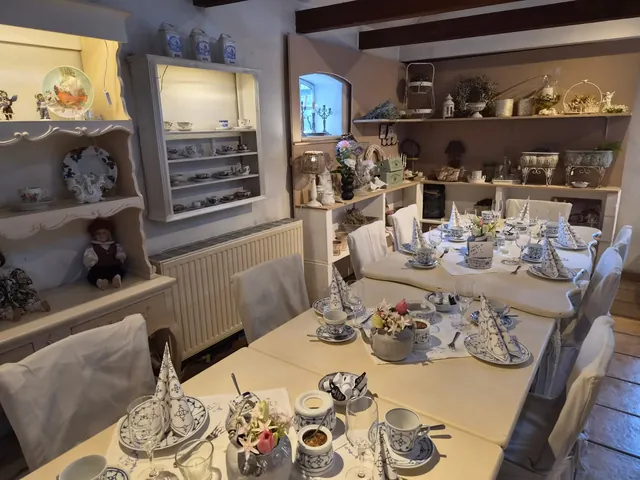 Gedeckte Tafel mit Indisch-Blau-Geschirr vor Regalen mit Porzellan und Dekoration